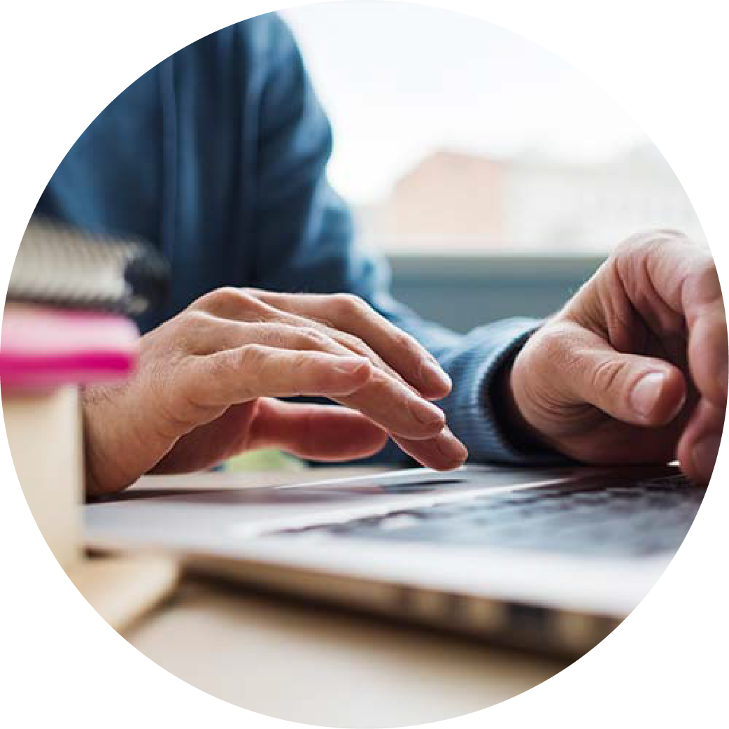 Person's hands typing on a laptop next to a stack of books. They are looking up resources about regional housing.